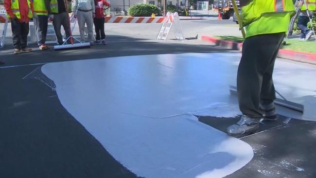 Trabalhadores pintando o asfalto de Phoenix de branco.