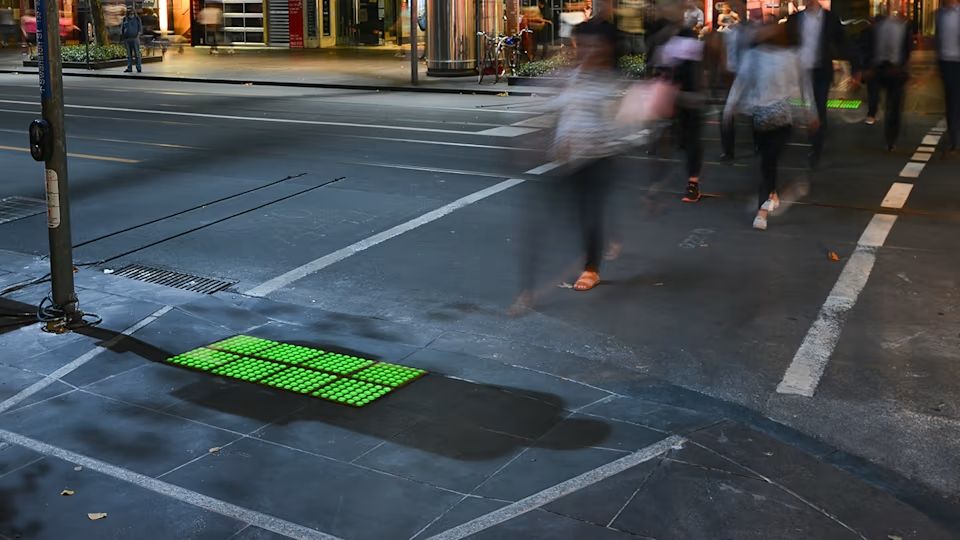 Fotografia de calçada em Melbourne com semáforo de piso embutido no piso tátil.